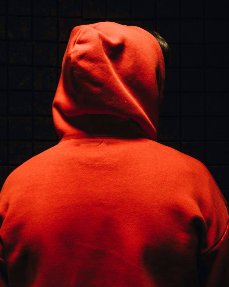 Capucha roja vista de espaldas sobre un fondo oscuro
