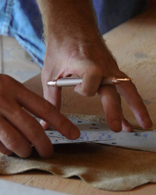 Manos marcando un patrón sobre una pieza de cuero