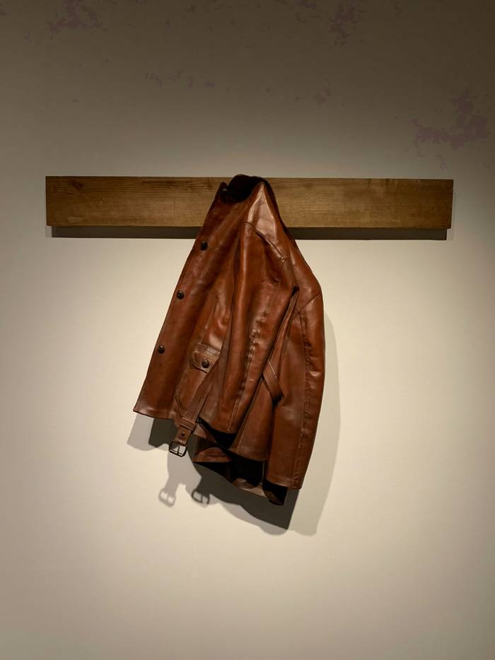 Chaqueta de cuero café colgada de un listón de madera