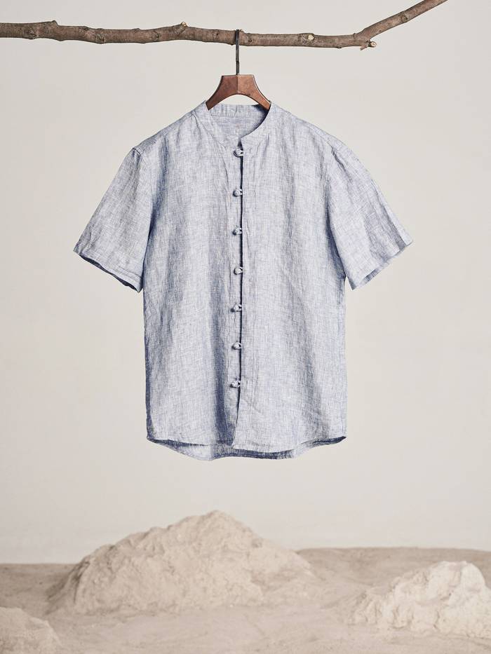 Camisa celeste de cuello mao colgada de una rama