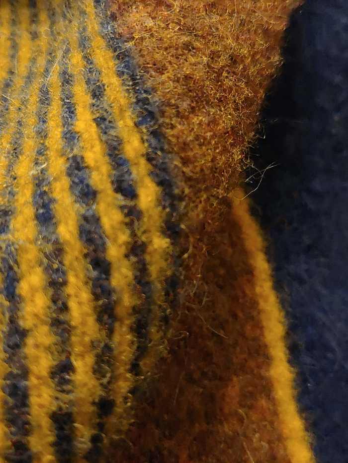 Primer plano de una lana tejida en franjas mostaza y azul marino