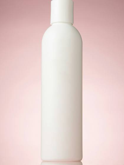 Botella blanca alta sobre un fondo rosado degradado