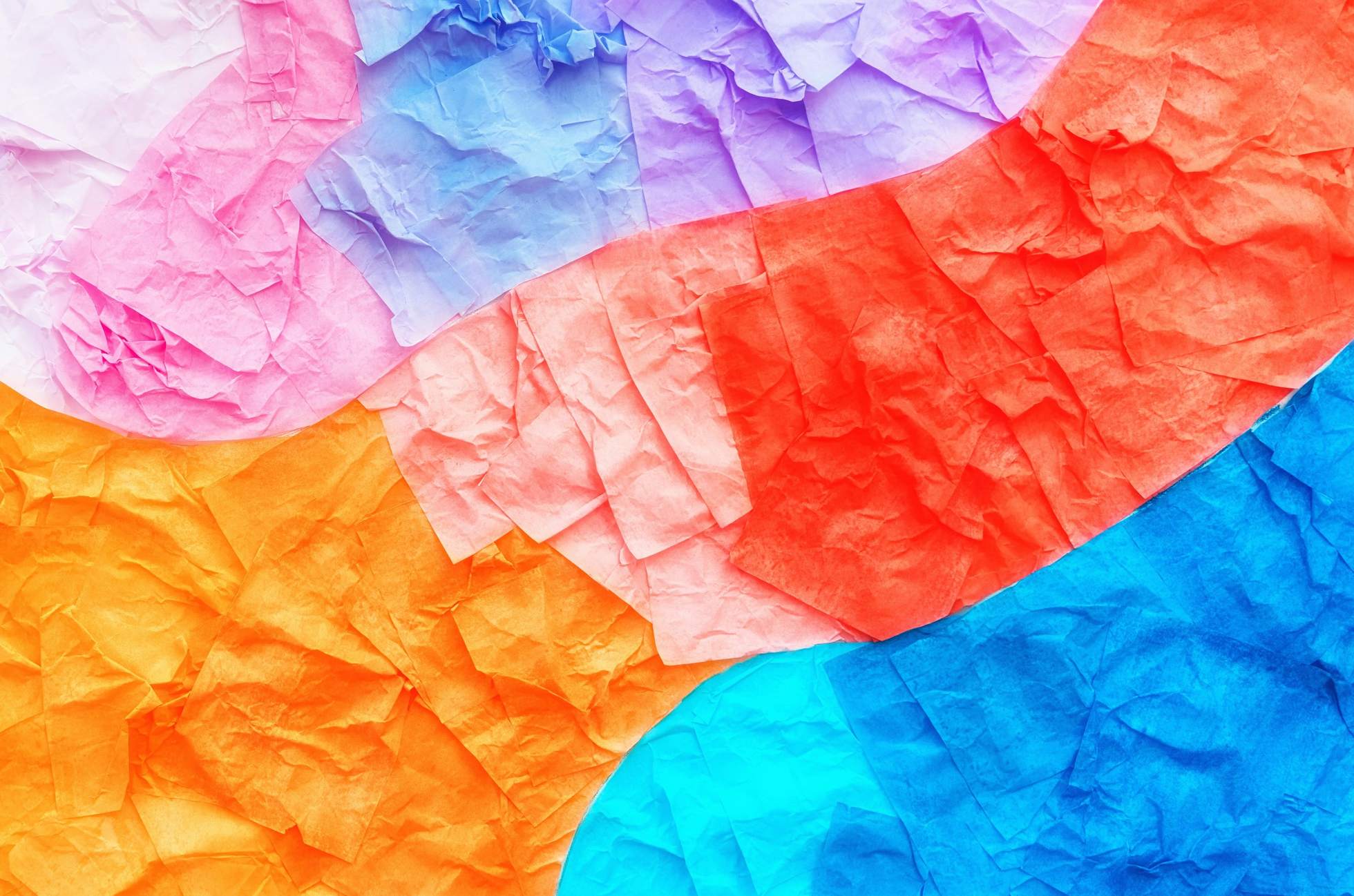 Papeles de colores rasgados y arrugados en rosa, naranjo, rojo y azul