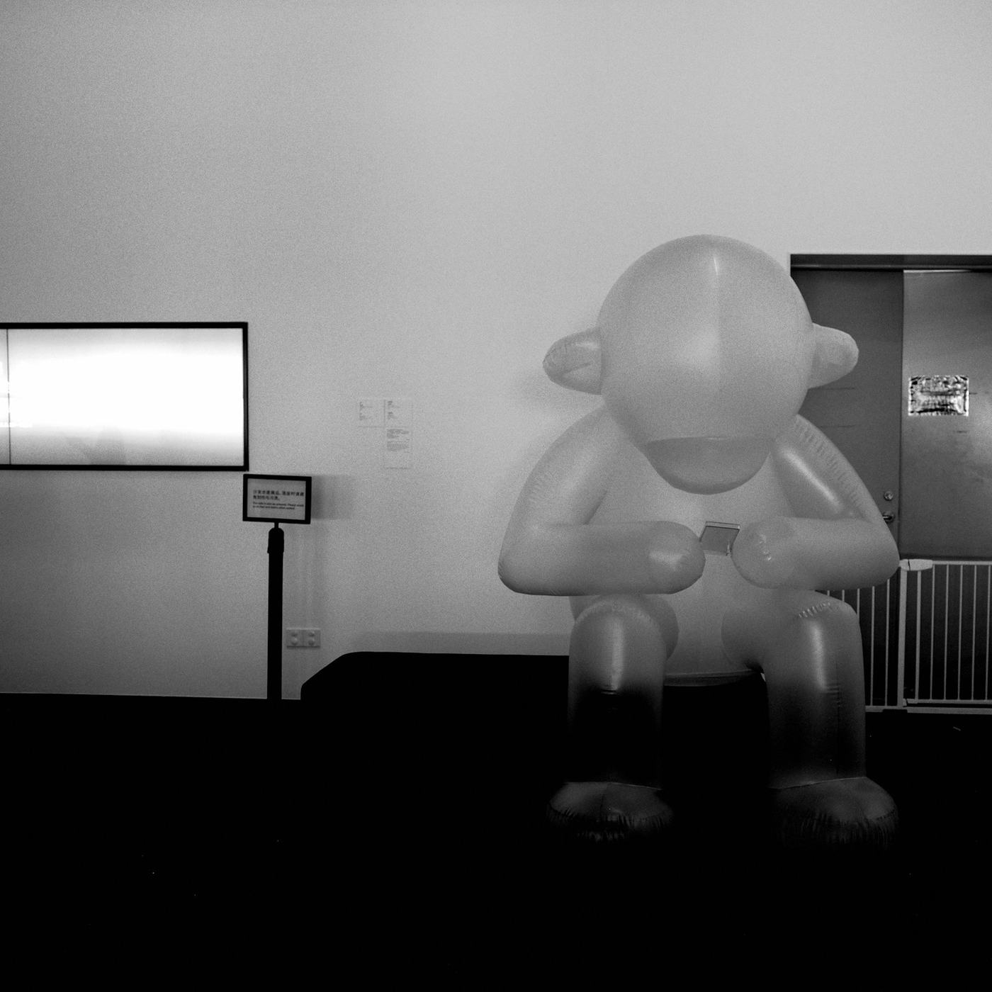 Figura inflable gris sentada en una sala, en blanco y negro