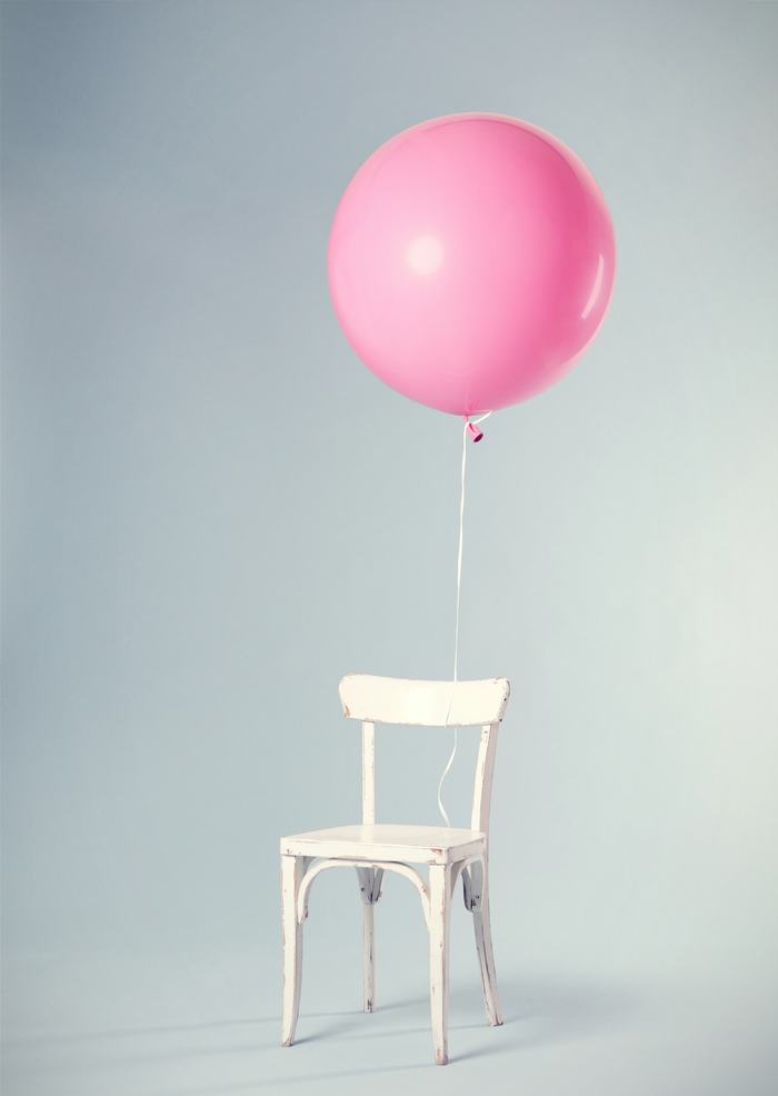 Un globo rosa atado a una silla blanca