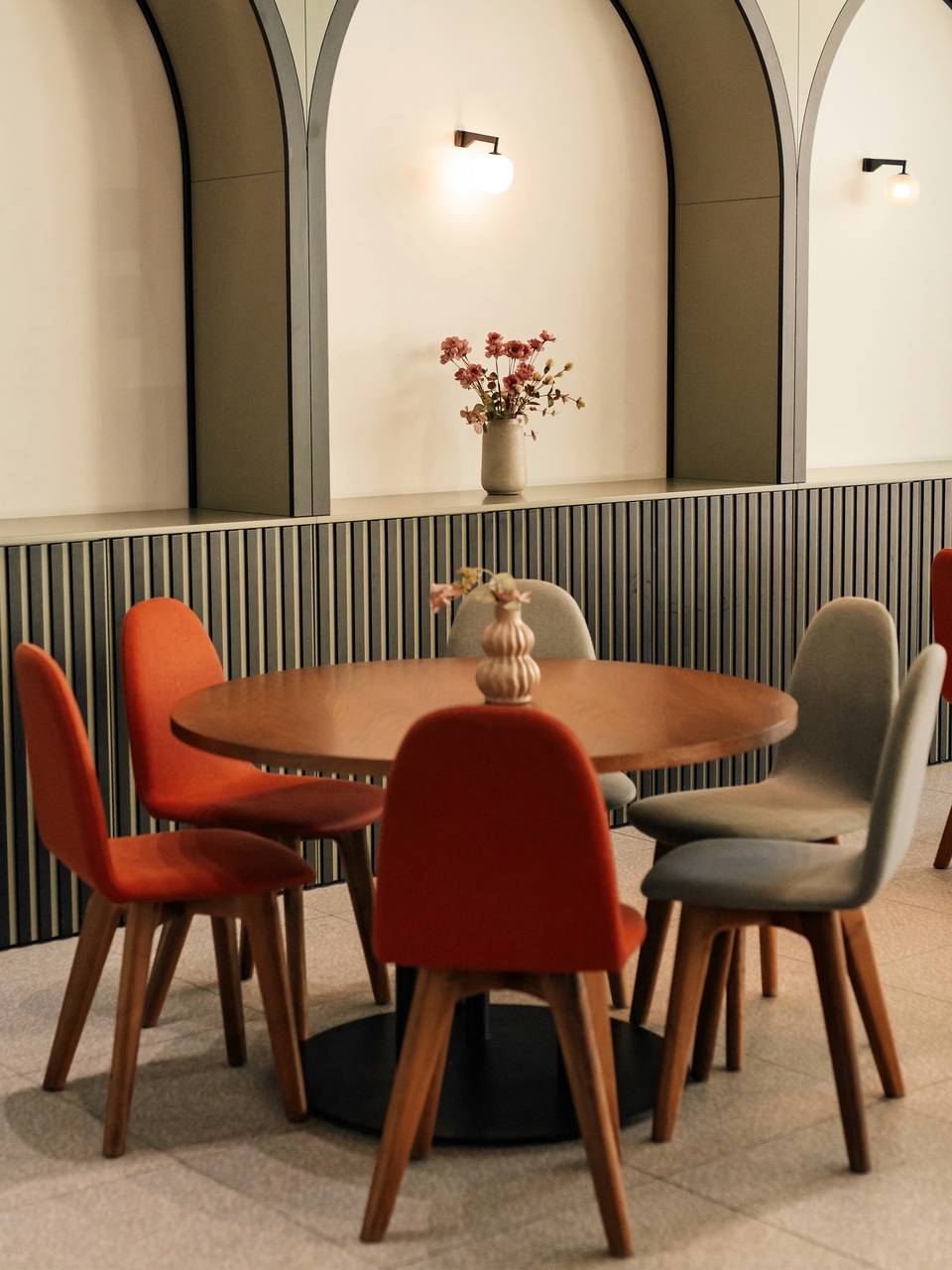Salón de un bar con arcos en la pared, mesa redonda y sillas terracota