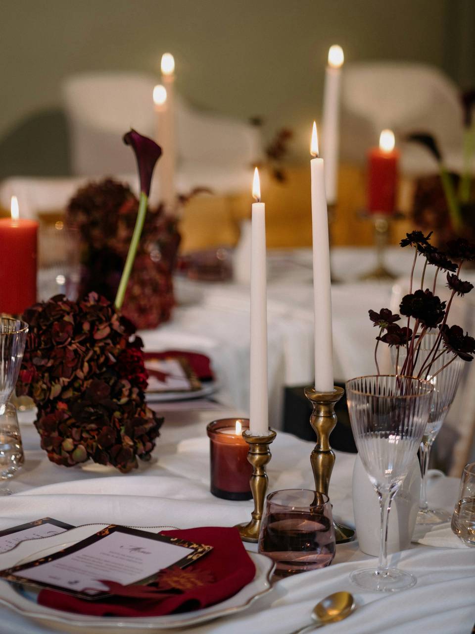 Mesa servida con velas altas, hortensias secas y copas