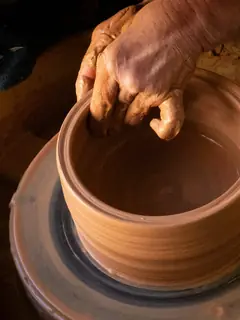 Manos moldeando arcilla rojiza en el torno