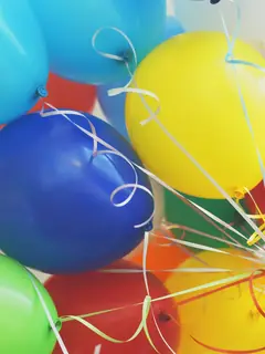Mano sosteniendo globos de colores