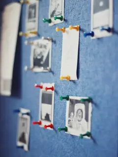 Fotografías en blanco y negro sujetas con chinchetas sobre un tablero azul