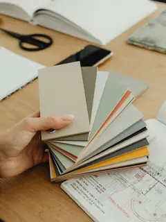 Mano con muestras de papel de colores sobre una mesa de trabajo