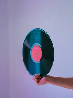 Brazo sosteniendo un disco de vinilo sobre un fondo lila