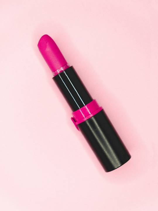 Labial fucsia sobre un fondo rosa claro