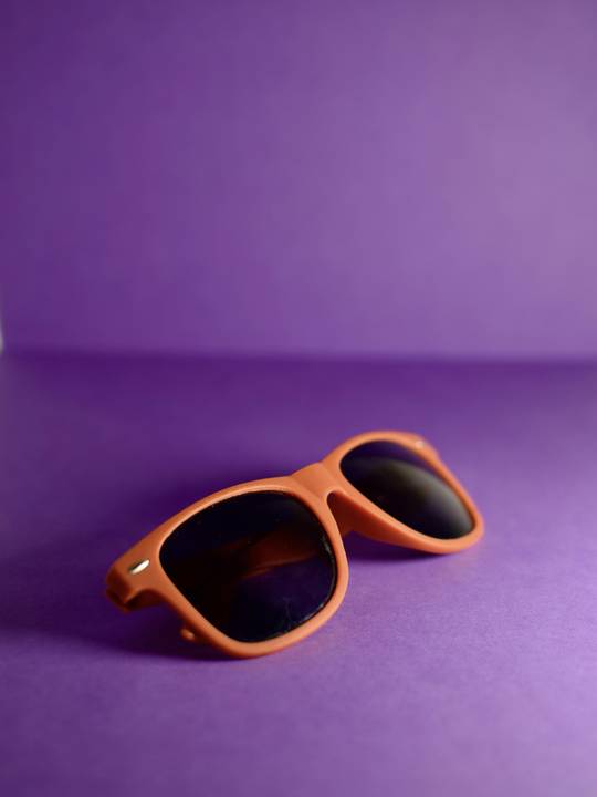 Gafas de sol anaranjadas sobre un fondo violeta