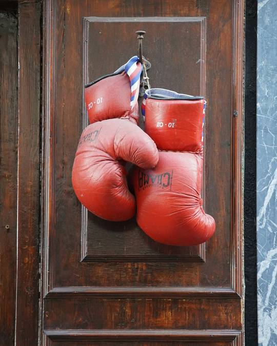 Guantes de boxeo rojos colgados de una puerta de madera