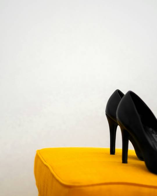 Zapatos negros de taco alto sobre un pouf amarillo