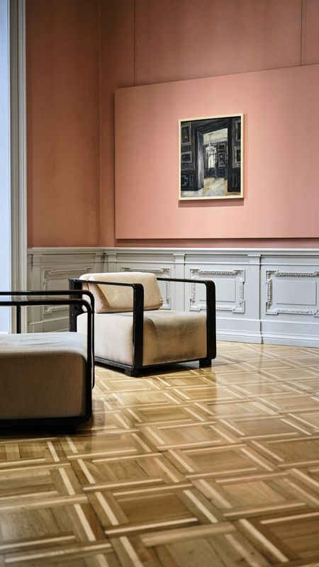 Sala con muros rosados, un cuadro pequeño y dos sillones bajos sobre un piso de parqué