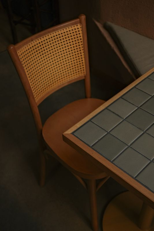 Silla de rejilla y una mesa con cubierta de baldosas, en una esquina en penumbra