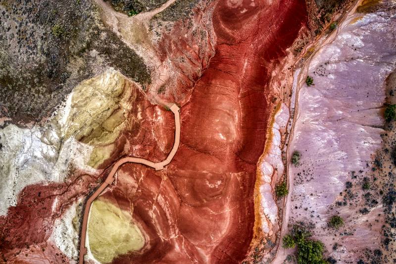 Terreno rojo y violáceo cruzado por un camino, visto desde el aire