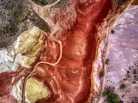Terreno rojo y violáceo cruzado por un camino, visto desde el aire