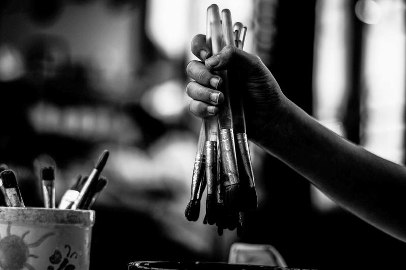 Una mano sostiene un manojo de pinceles en blanco y negro