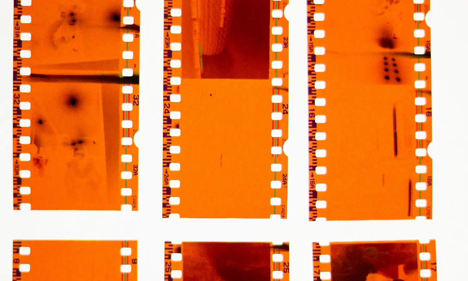 Tiras de negativos color naranja sobre una mesa de luz