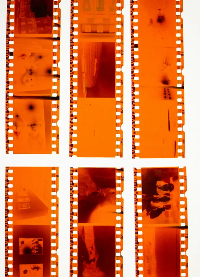 Tiras de negativos color naranja sobre una mesa de luz