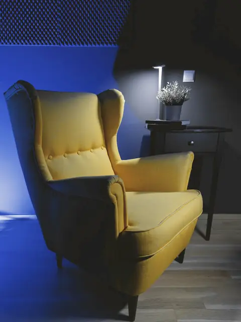 Sillón de orejas amarillo junto a una pared azul