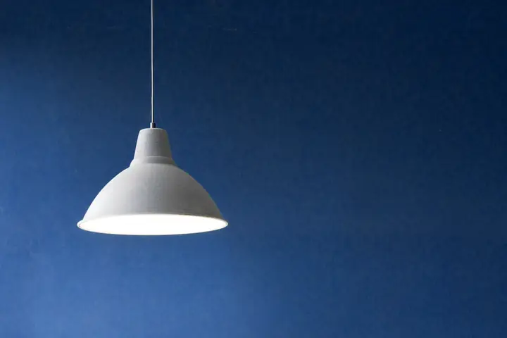 Lámpara colgante blanca sobre una pared turquesa