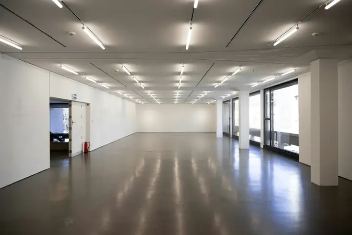 Sala amplia de paredes blancas con luces lineales en el techo