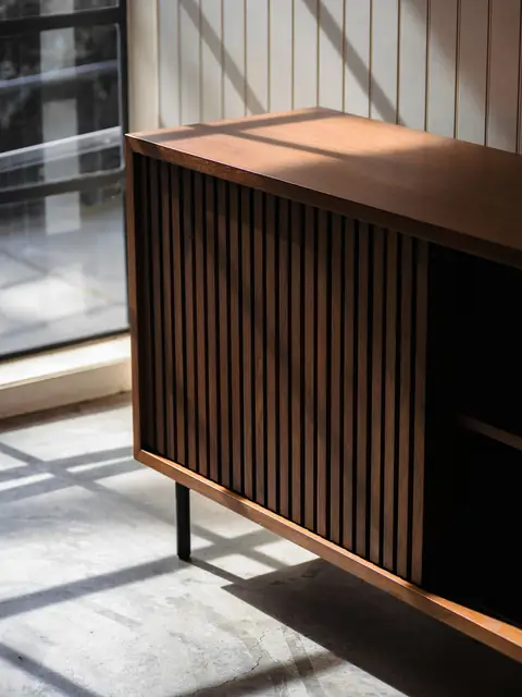 Aparador de madera con puertas de listones y luz de tarde