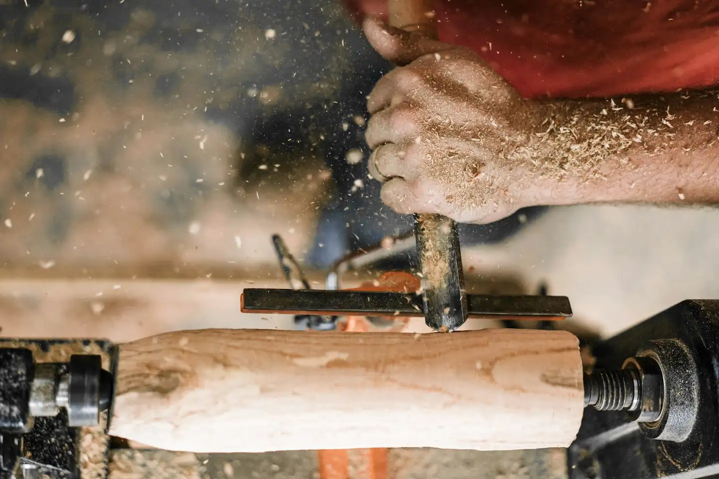 Manos tallando un trozo de madera en un torno