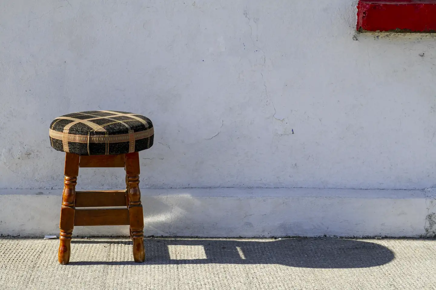 Taburete de asiento a cuadros contra un muro blanco