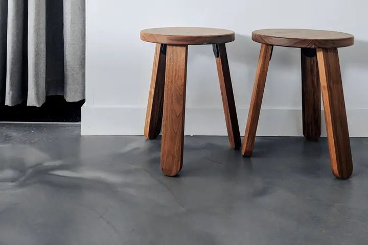 Dos taburetes bajos de madera junto a una cortina