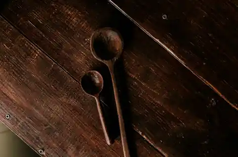 Dos cucharas de madera oscura sobre tablas