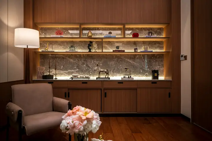 Estantería de madera con luz cálida y un sillón rosado