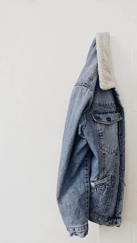 Chaqueta de mezclilla colgada de un clavo sobre una pared clara