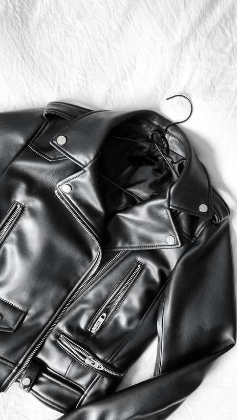 Chaqueta de cuero negro con cierre diagonal sobre una tela blanca