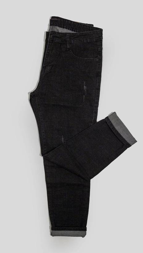 Pantalón de mezclilla negra doblado sobre un fondo gris