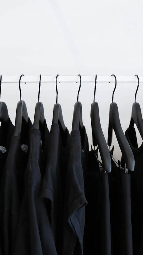 Fila de prendas negras en perchas negras