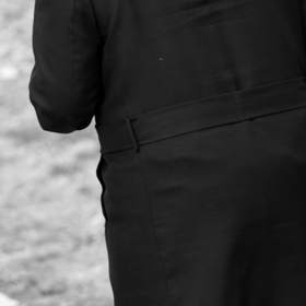 Figura de espaldas con sombrero y abrigo largo, en blanco y negro