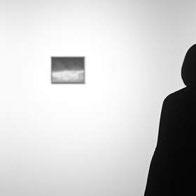 Silueta de una persona ante una pared blanca con pequeños cuadros