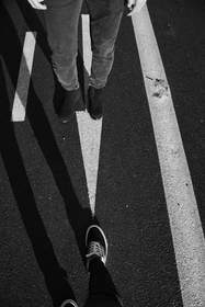 Pies que cruzan una calle con franjas de sombra