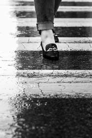 Mocasín negro sobre un paso peatonal mojado, en blanco y negro