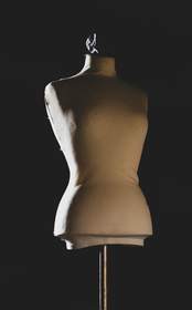 Maniquí de sastre color crudo sobre un fondo negro