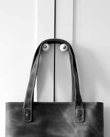 Bolso de cuero caramelo colgado de una puerta blanca