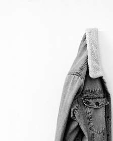 Chaqueta de mezclilla colgada de un clavo sobre una pared clara