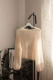 Suéter de mohair claro colgado junto a una cortina