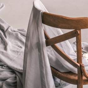 Tela gris colgada sobre el respaldo de una silla de madera