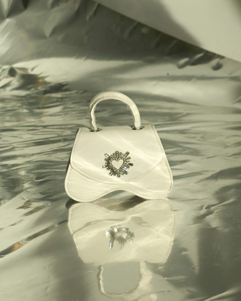 Bolso blanco de mano sobre una lámina metálica plateada